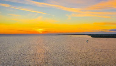 Hava görüntüsü. Mavi denizde sörf yapan uçurtma. Arka planda güzel bulutlar.