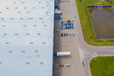 Çatıda güneş panelleri ve birçok kamyonla Endüstriyel Depolama Alanının Havadan Üst Görünümü.