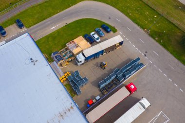 Malzeme deposunun havadan görüntüsü. Sanayi bölgesindeki lojistik merkezi yukarıdan. Lojistik merkezde yüklenen kamyonların hava görüntüsü. İnsansız hava aracından görüntüle.