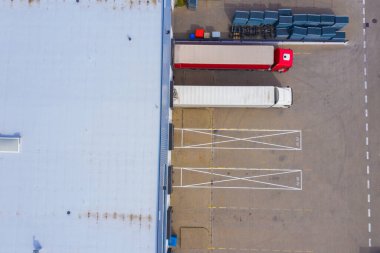 Malzeme deposunun havadan görüntüsü. Sanayi bölgesindeki lojistik merkezi yukarıdan. Lojistik merkezde yüklenen kamyonların hava görüntüsü. İnsansız hava aracından görüntüle.