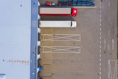 Malzeme deposunun havadan görüntüsü. Sanayi bölgesindeki lojistik merkezi yukarıdan. Lojistik merkezde yüklenen kamyonların hava görüntüsü. İnsansız hava aracından görüntüle.