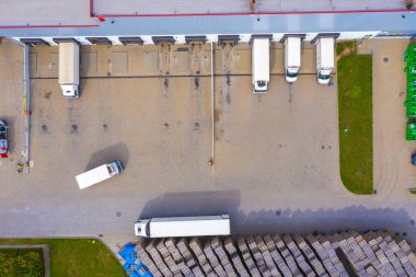 Malzeme deposunun havadan görüntüsü. Sanayi bölgesindeki lojistik merkezi yukarıdan. Lojistik merkezde yüklenen kamyonların hava görüntüsü