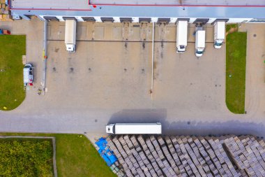 Malzeme deposunun havadan görüntüsü. Sanayi bölgesindeki lojistik merkezi yukarıdan. Lojistik merkezde yüklenen kamyonların hava görüntüsü