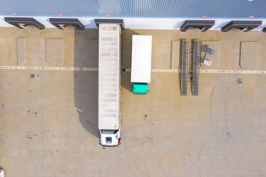 Malzeme deposunun havadan görüntüsü. Sanayi bölgesindeki lojistik merkezi yukarıdan. Lojistik merkezde yüklenen kamyonların hava görüntüsü. İnsansız hava aracından görüntüle.