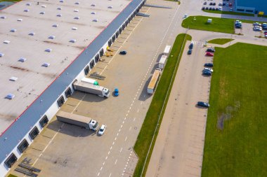 Malzeme deposunun havadan görüntüsü. Sanayi bölgesindeki lojistik merkezi yukarıdan. Lojistik merkezde yüklenen kamyonların hava görüntüsü. İnsansız hava aracından görüntüle.