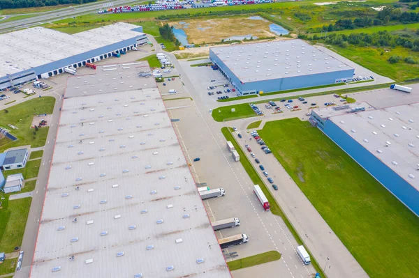 Aerial Shot of Industrial Warehouse Loading Dock where Many Truck with Semi Trailers Load Merchandise.