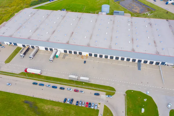 Aerial Shot of Industrial Warehouse Loading Dock where Many Truck with Semi Trailers Load Merchandise.