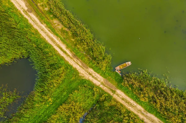 Top down aerial view of small rowing boat near coast of lake