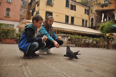 Venedik, bir yaya Caddesi üzerinde çocuklar tarafından ekmek kırıntısı beslenen güvercinler.
