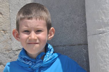 Süt dişleri, bir gömlek ve güneşli bir günde gülüyor bir bandaj ile kasvetli bir çocuk.