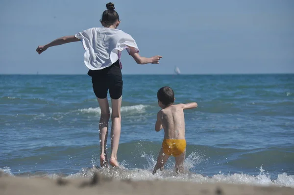 Çocuklar, deniz kıyısında oynayan kardeşler. Dalgalar halinde atlama.