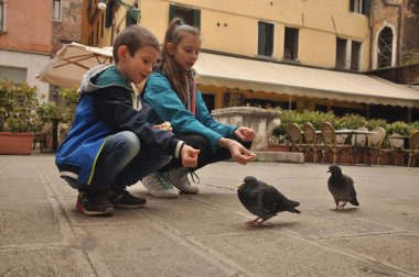 Venedik, bir yaya Caddesi üzerinde çocuklar tarafından ekmek kırıntısı beslenen güvercinler.