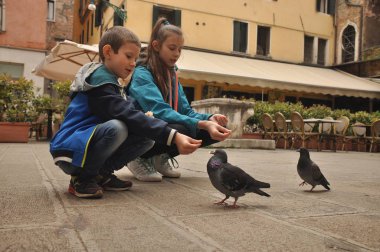 Venedik, bir yaya Caddesi üzerinde çocuklar tarafından ekmek kırıntısı beslenen güvercinler.