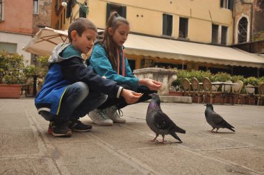 Venedik, bir yaya Caddesi üzerinde çocuklar tarafından ekmek kırıntısı beslenen güvercinler.