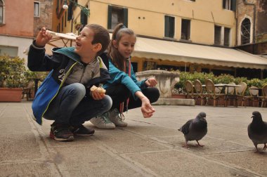 Venedik, bir yaya Caddesi üzerinde çocuklar tarafından ekmek kırıntısı beslenen güvercinler.