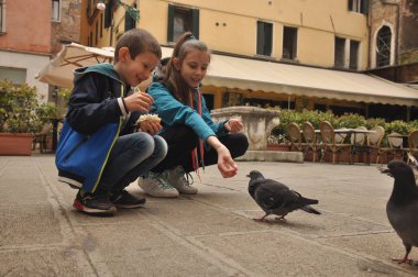 Venedik, bir yaya Caddesi üzerinde çocuklar tarafından ekmek kırıntısı beslenen güvercinler.
