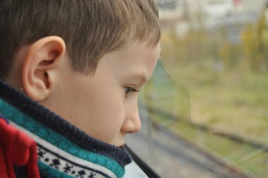 Çocuk pencerenin altından şehri izliyor.