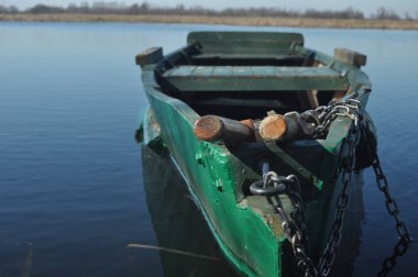 Kürek teknesi kıyıya demirlemiş. Nehirde bahar. Yüzen.