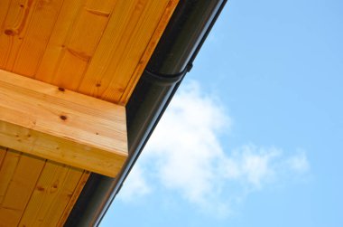 Düşük açılı ahşap panelli çatının mavi gökyüzü arka planında drenajı.