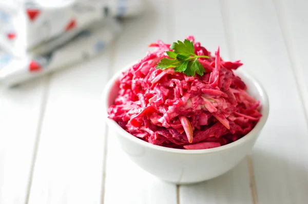 Salad from grated beets on a white background with a sprig of parsley