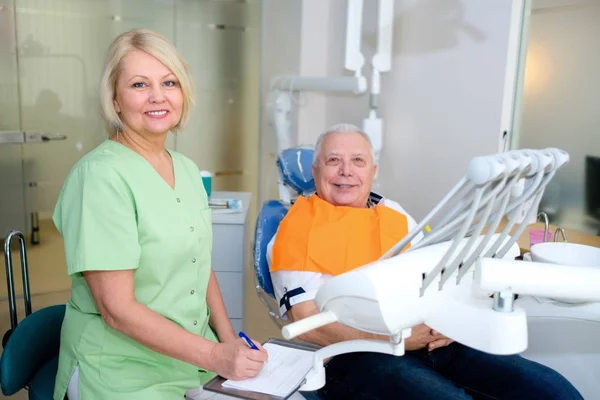 歯科医院で一緒にカメラを見て歯科医の女性とシニア男性患者 高齢者の歯科治療歯科 ヘルスケアの概念 — ストック写真