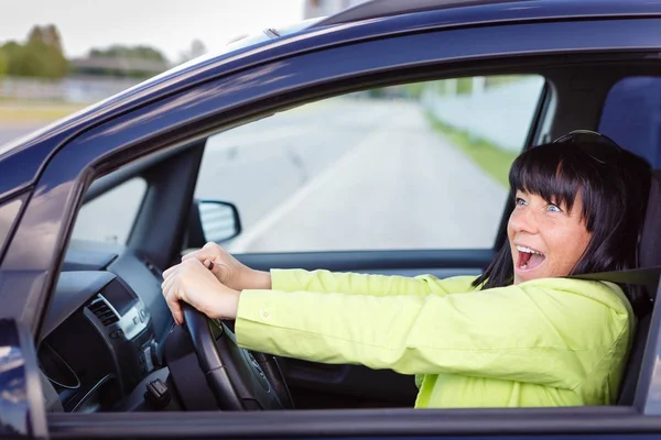 Scared and surprised woman with big eyes shouts driving the car - outdoors