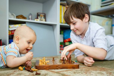 İki çocuk erkek çocuk odasında yerde yatan satranç oynarken