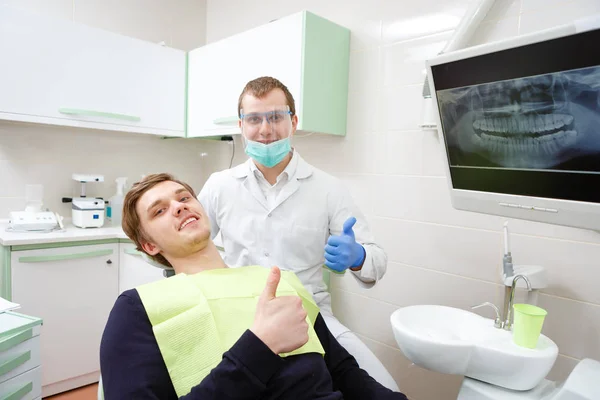 快乐微笑的男性患者和年轻的牙医在牙科诊所检查时 在X光背景 竖起大拇指 为人们提供牙科护理 医学和保健概念 — 图库照片