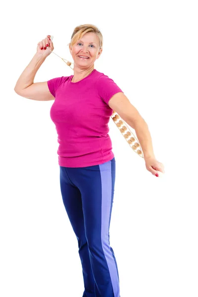 Happy and smile old senior woman dressed in t-shirt color Marsala doing sport fitness exercises with manual wooden masseur for massage of a back, isolated on white background, Positive emotions
