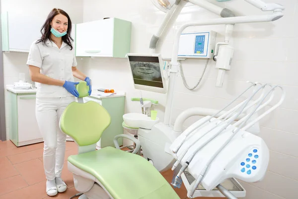歯科医院で歯科医の椅子に寄りかかっている笑顔の若い歯科医女性の肖像画 — ストック写真