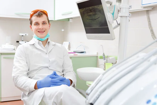 Portret Szczęśliwego Uśmiechnął Młodego Męskiego Dentysty Siedzącego Krześle Kliniki Stomatologicznej — Zdjęcie stockowe