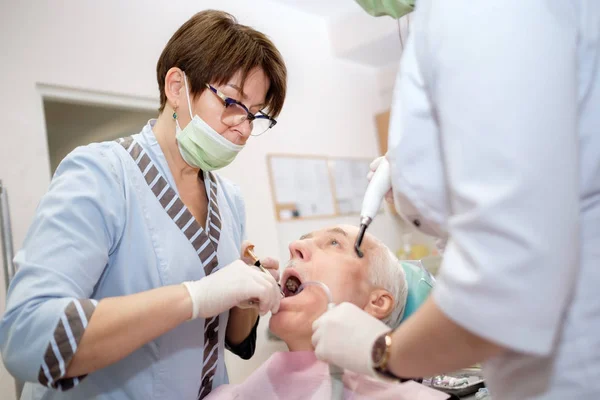 Dental treatment by filling the decay for senior male patient. And make ultraviolet rays to solidify the material. Dental care for older people. Dentistry, medicine and health care concept