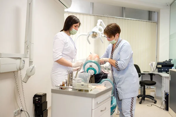 Dentist and nurse making professional teeth cleaning male senior patient at the dental office. Dental care for older people. Dentistry, medicine and health care concept