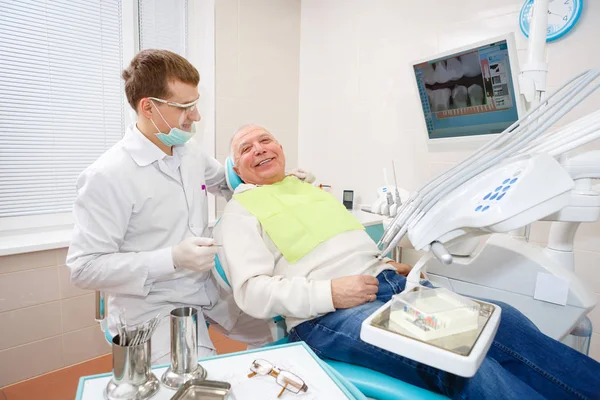 若い医師の歯科医と老人の患者 笑顔とカメラを見て — ストック写真