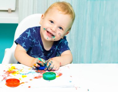 Parmak boyalarıyla çizen sarışın bir bebek var. Erken kalkınma kavramı