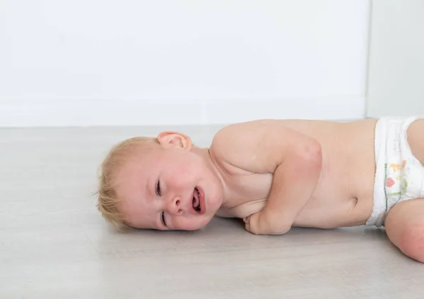 Bebê loira menino chorando deitado no campo. — Fotografia de Stock