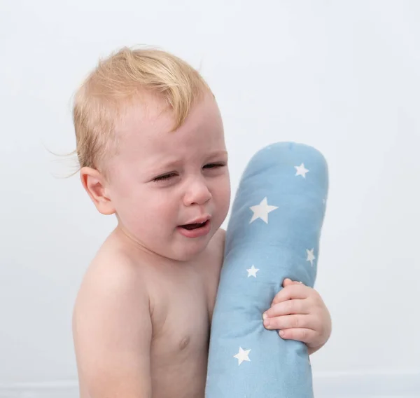 Loira bebê menino chorando abraçando um travesseiro. — Fotografia de Stock
