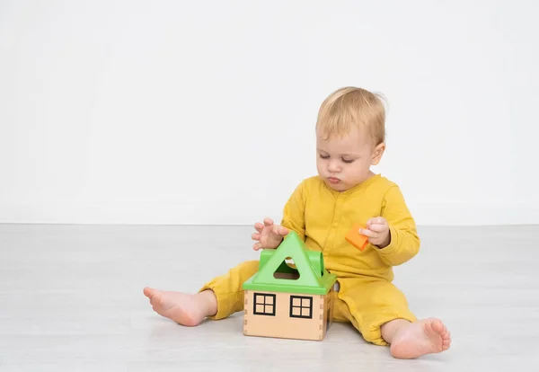 Adorable garçon heureux tout-petit assis au sol et jouer avec un trieur de jouets. — Photo