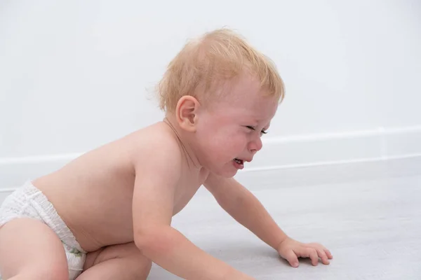 Bebê loira menino chorando deitado no campo. — Fotografia de Stock