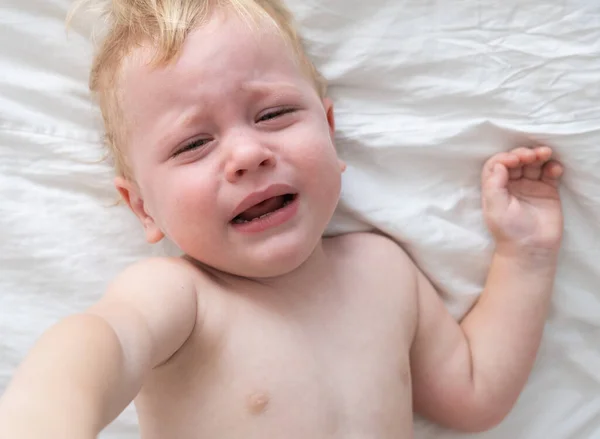 Menino chorando deitado na cama. — Fotografia de Stock