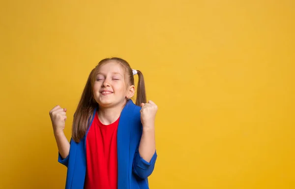 yes success and achievement. Portrait of nice young girl making a win gesture with close eyes on yellow background
