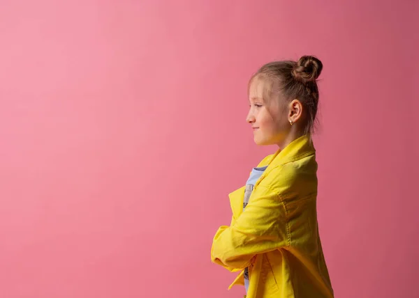 Veselé děvče ve žluté bundě hledající prázdné místo, reklama. studio záběr na pastelové růžové pozadí — Stock fotografie