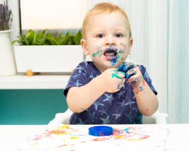 Kirli çocuk parmaklarıyla resim çiziyor.