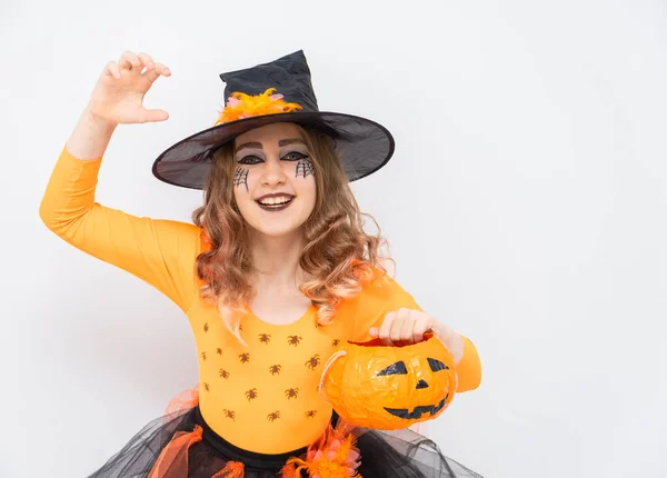 Fiatalabb szőke lány narancs boszorkány jelmez cukorka vödör tök Halloween fehér háttér. — Stock Fotó