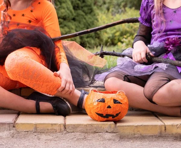 Halloween gyerek lányok jelmez boszorkányok ül az úton egy tök. — Stock Fotó
