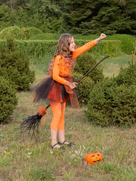 Halloween criança menina traje bruxas sentado em uma vassoura ao ar livre. — Fotografia de Stock