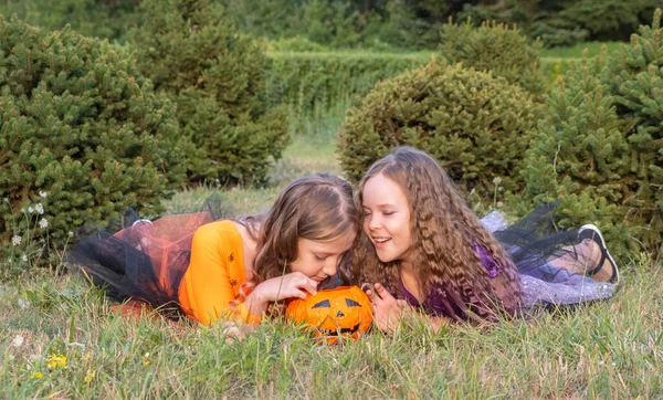 Halloween gyerek lányok jelmez boszorkányok feküdt a füvön Nézi Halloween Candy. — Stock Fotó