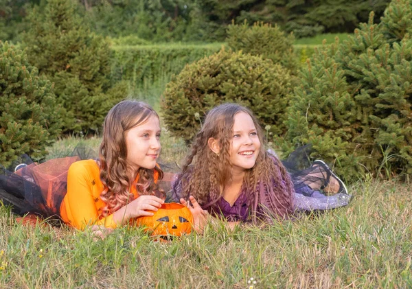 Halloween gyerek lányok jelmez boszorkányok feküdt a füvön Nézi Halloween Candy. — Stock Fotó