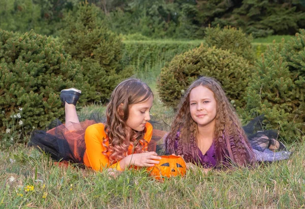 Halloween dziecko dziewczyny kostium czarownice leżące na trawie patrząc na Halloween Candy. — Zdjęcie stockowe