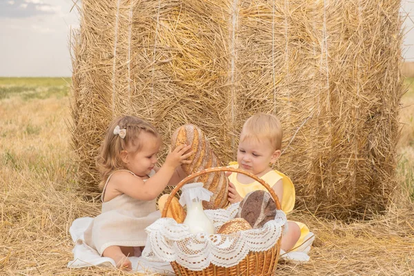 Блондин и девочка сидят на сене с корзиной хлеба. — стоковое фото